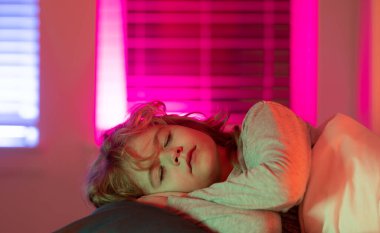 Gece uykusu. Çocuk yatakta uyuyor. Çocuk battaniyenin altında uyuyor, yastığın üzerinde yatıyor. Çocuk uyuyor, sağlıklı bir uyku çekiyor ya da kestiriyor.