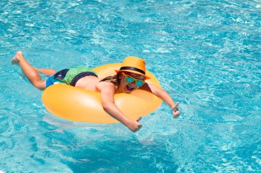 Yaz eğlencesi. Çocuk yüzme havuzunda su sıçratıyor. Çocukla yaz tatilinde su sporu aktivitesi. Çocuk oyuncakları, yüzen yüzük