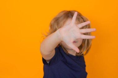 Çocuk izole edilmiş stüdyo geçmişinde jest yapıyor. Uyarı sembolü gösteren çocuk, hayır işareti. Çocuk koruma, zorbalık, istismar ve şiddet kavramı