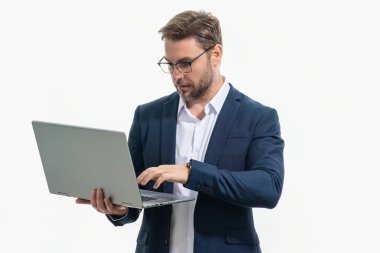 Bir dizüstü bilgisayarla çalışan girişimci. İş adamı stüdyo arka planında dizüstü bilgisayar kullanıyor. Gözlüklü, düşünceli beyaz iş adamı bilgisayar ekranına bakıyor, internette çalışıyor, serbest çalışıyor.