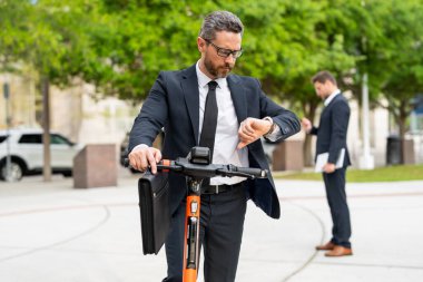 New York parkında scooter süren çekici bir iş adamı. İş toplantısında elektrikli scooter kullanan takım elbiseli bir iş adamı. Orta yaşlı iş adamı takım elbiseli scooter kullanıyor.