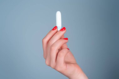 El ele tutuşan adet tamponu. Kadınların regl sancıları. Kadınsı tampon. Kadının elinde hijyenik tampon var. Kritik günler, tamponlar. Kadınlar ve jinekolojik sağlık hizmetleri. Pamuk tampon
