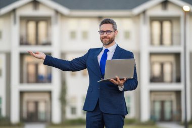 Dışarıda dizüstü bilgisayarda çalışan bir adam. Adam dizüstü bilgisayardaki e-postaları kontrol ediyor, sosyal ağda mesaj yazıyor, interneti kullanıyor, dışarıdaki bilgisayarlarda bilgi arıyor. Ev yakınlarında dizüstü bilgisayar kullanan bir adam.