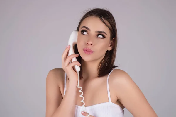 Brunette woman talking on retro line phone. Portrait of woman holding vintage telephone. Pin up girl with phone handset. Retro vintage phone handset. Pinup style girl of woman holding telephone tube