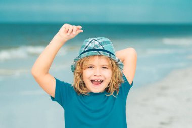 Yaz tatili kavramı. Kumsalda yürüyen mutlu küçük çocuk. Seyahat ve macera çocuk konsepti. Güzel çocuk dışarıda oynuyor. Hayalci çocuk suratı. Hayalperest çocuk portresi yakın plan. Hayaller ve