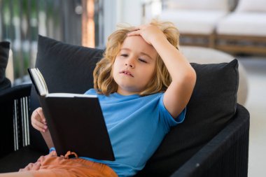 Hayali çocuk. Odadaki kanepede uzanmış kitap okuyan sıradan giyinmiş tatlı bir çocuk.