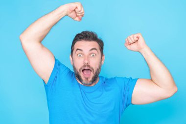 Stüdyo arka planında izole edilmiş milenyum insanının şaşırmış yüzü. Yakışıklı mutlu genç adam, kazanan hareketi gösteriyor. Kolları açık başarılı bir adam. Şok olmuş heyecanlı adam el kaldırsın.