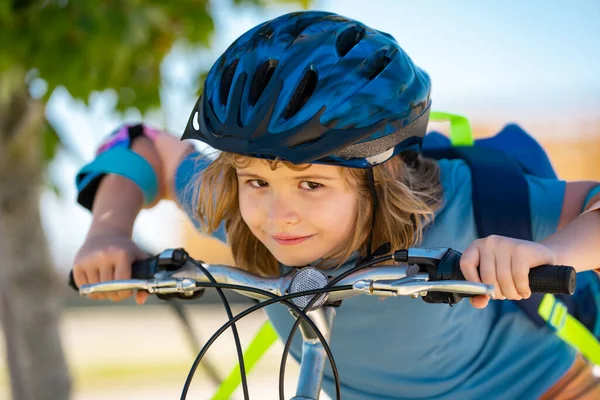 Parkta bisiklete binen sportif bir çocuk. Bisiklet süren kasklı çocuk. Çocuk bisiklet sürmeyi öğreniyor. Bisikletli çocuklar. Kasklı mutlu çocuk dışarıda bisiklet sürüyor. Çocuklarla spor eğlencesi.