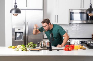 Aşçı adam mutfakta tencerede yemek pişiriyor. Gurme yemeği hazırlama süreci. Adam evde yemek pişiriyor, esrar kullanıyor. Şef yemek pişiriyor. Yakışıklı aşçı aşçı konsepti