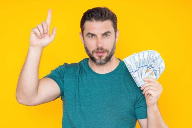 Adam sarı stüdyonun arka planına para koydu. Dolar banknotları olan zengin adamın portresi. Dolar banknotları olan başarılı bir adam. Zengin milyoner.