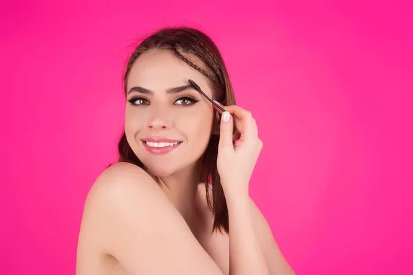 Woman shaping brown eyebrows. Woman eye with beautiful eyebrows. Shaped brows, long eyelashes. Paint eyebrows. Girl contouring eyebrows on isolated studio background