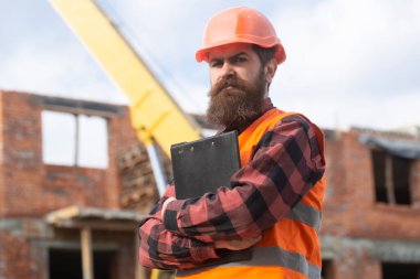 İnşaatçının portresi. İnşaat alanında miğferli bir işçi poz veriyor.