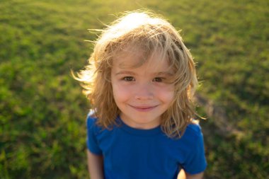 Çocuk portresi doğada, parkta ya da dışarıda. Yazlık parkta oynayan mutlu çocuğun yüzünü kapat.