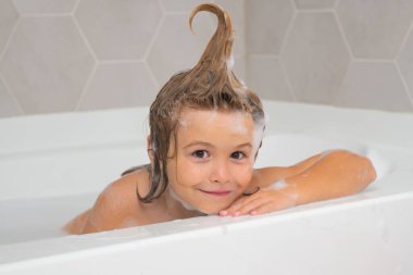 Yüzü köpüklü çocuklar gibi. Küvette küçük bir çocuk. Banyoda yıkanmak. Saçında sabun köpüğü olan çocuk banyo yapıyor. Gülümseyen çocuğun, sağlık hizmetlerinin ve çocuk hijyeninin yakın plan portresi