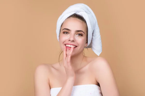 Woman applying eye patches. Close up portrait girl with towel on head and patches under eyes. Portrait of beauty woman with eye patches and perfect skin. Morning skincare routine