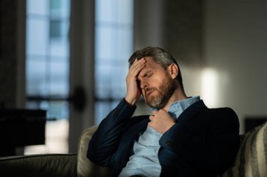 Baş ağrısı, yorgunluk ve stres. Takım elbiseli adamın yakın plan portresi baş ağrısı yapıyor. Baş ağrısı konsepti. Ofiste acılı adamlar streslidir. Stresli ve baş ağrısı