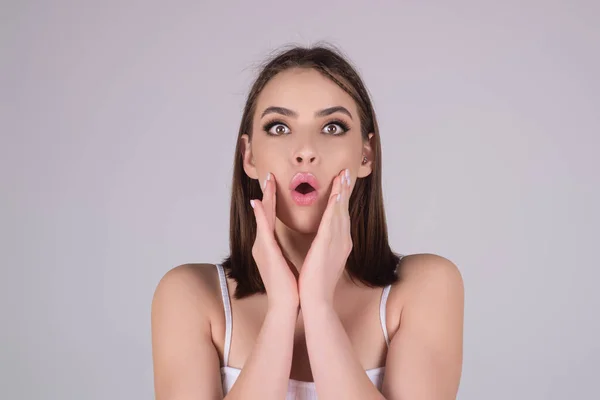 Shocked face of woman shouting WOW, isolated on studio background with copy space. Shock content. Girl looks with terrified expression, shocking news. Woman shocked face with open mouth and big eyes