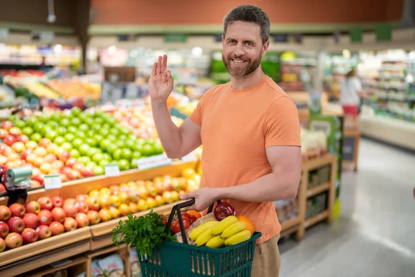 Portrait of hispanic man with shopping basket purchasing food in grocery store. Sales and shopping. Man buying products at supermarket. Supermarket and grocery shop. Discount, sale concept