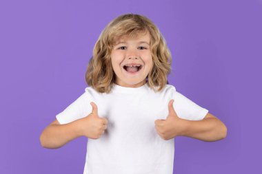Excited kid boy with thumbs up on studio isolated background. Surprised face, amazed emotions of child