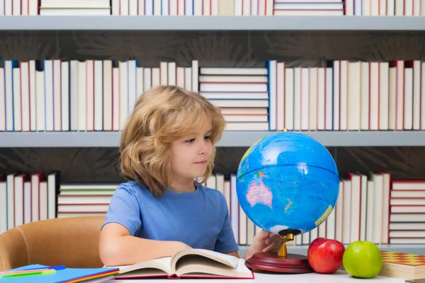 小学校の図書館で地球を見ている生徒 オタクの小学生だ 本を持って小学生から賢い子供 賢い天才知能の子供は学ぶ準備ができている 世界中で — ストック写真
