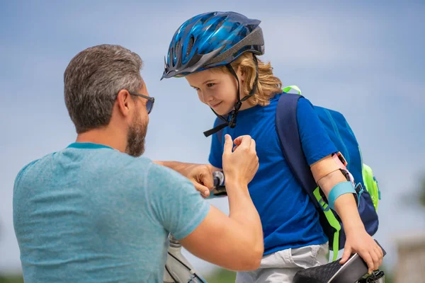 Fathers day. Father teaching son ride a bicycle. Father helping his son to wear a cycling helmet. Child in safety helmet. Father support child. Fathers love. Sporty kids