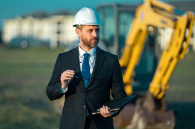 Mühendis, inşaat müdürü ya da bir inşaatta yönetici. Takım elbiseli ve kasklı bir yönetici. Yatırımcı, inşaat müdürü. Geliştirici, açık hava portresi. Orta yaşlı mimar