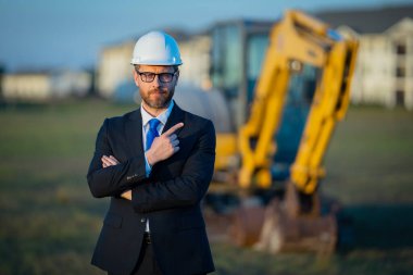 İnşaat mühendisi ya da inşaat mühendisi. İnşaat alanında kask ve takım elbiseli mühendis. Kazıcının yanındaki inşaat müdürü. Yenileme konsepti