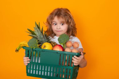 Alışveriş sepetli çocuk. Stüdyo, marketteki şirin çocuğun izole edilmiş portresi.