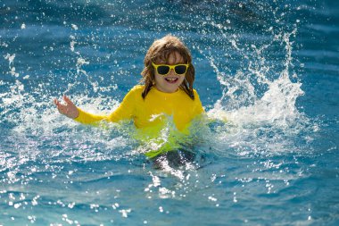Çocuk yaz tatilinin tadını çıkarıyor, havuzda yüzüyor. Çocuk yaz tatilinde bilardoda eğleniyor. Havuz suyunda oynayan mutlu çocuklar. Yaz tatilindeki mutlu çocuklar yüzme havuzunda suda oynuyorlar.
