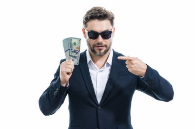 İyi ödeme. Yakışıklı bir iş adamı, gri stüdyoda izole edilmiş para tutuyor. Dolar banknotları halinde para. Yığınla para, finans, yatırım ve tasarruf