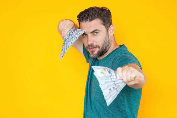 Man holding cash money in dollar banknotes on isolated yellow background. Studio portrait of businessman with bunch of dollar banknotes. Dollar money concept. Career wealth business. Cash dollar