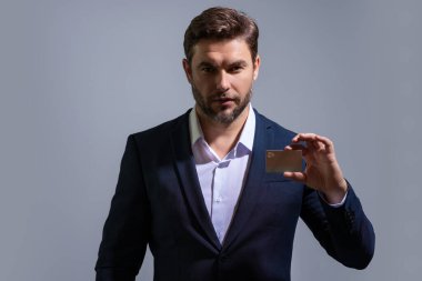 Gri arka planda kredi kartı olan bir adamın stüdyo portresi. Para yönetimi ve kredi puanı. Ödül parası. Kredi limiti. İnternetten alışveriş konsepti. Kredi geçmişi. Finansal sorumluluk