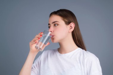 Stüdyonun arka planında izole edilmiş taze bir bardak su içen genç bir kadın. Susamış bir kadın cam içecekler tutuyor susuzluğu, su dengesini, sağlıklı yaşam tarzını engelliyor.