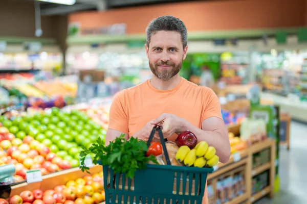 Man with grocery basket shopping at supermarket. Grocery store, shopping basket. Banner with man for grocery food store or supermarket. Man choosing food in store or grocery store