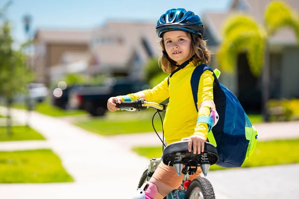 Küçük çocuk yaz parkında bisiklet sürüyor. Çocuk dışarıda bir garaj yolunda bisiklet sürüyor. Şehirde kask takan bisikletli bir çocuk. Bisikletli çocuk dışarıda. Amerikan mahallesinde bisiklet süren bir çocuk.
