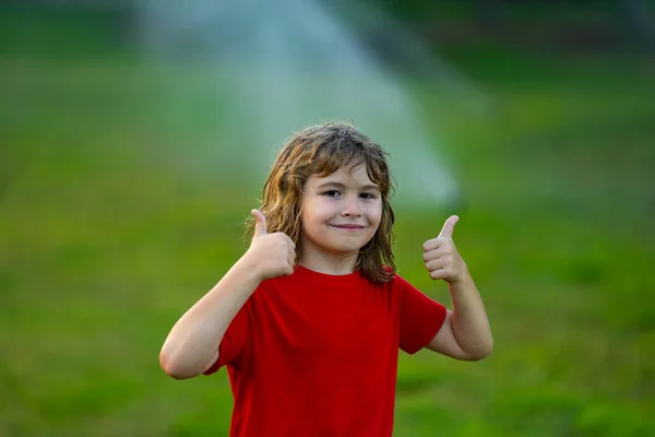 Child play near automatic sprayers in the garden. Watering in the garden. Kid freshness of nature. Automatic lawn sprinkler watering grass. Garden irrigation system watering lawn. Sprinkler system