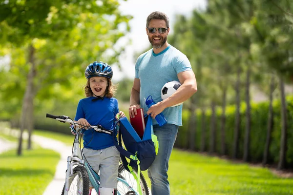 Father helping son get ready for school. Father and son ride a bicycle. Fathers support and helping son. Fathers day concept. Father and son friends. Child care