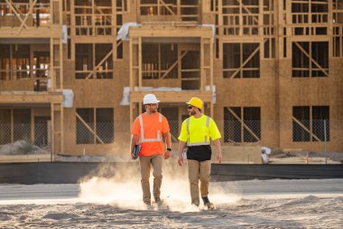 İnşaat işçileri kask takarak çok çalışıyor. Sert şapkalı iki işçi bina inşa ederken güvenliği sağlamaktan sorumludur. İnşaatçılar kişisel koruyucu ekipman