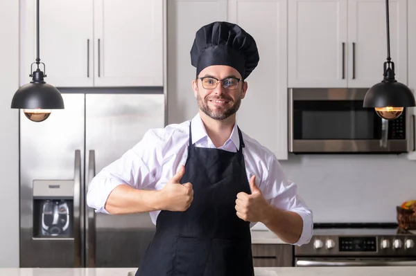 親指を立てて幸せなパン屋 キッチンでの均一な調理でハンサムな男のシェフ レストランメニューのコンセプト パン屋の制服を着たヒスパニック系の男 料理と料理 — ストック写真