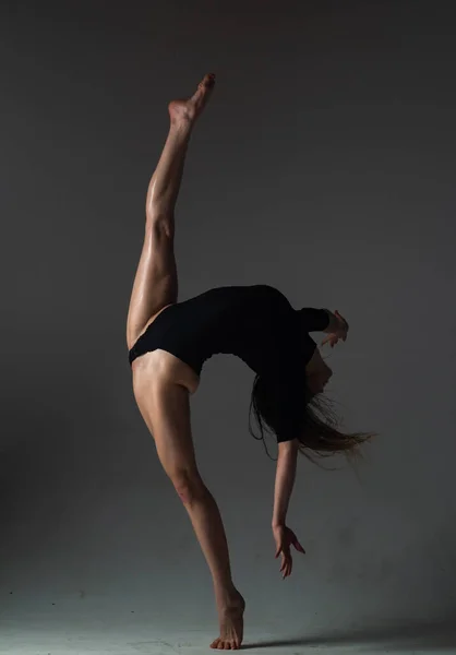 脚スプリット 柔軟な少女はストレッチのために体操を行います 美しいセクシーな柔軟な女性は セクシーな柔軟なボディを示しています 黒に伸びる柔軟性 強い柔軟な女性のボディ — ストック写真