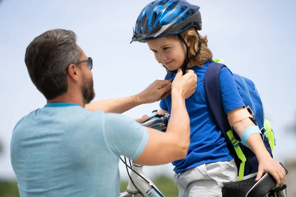 Insurance child. Father teaching son cycling on bike. Father learn little son to ride a bicycle. Father support and helping son. Fathers day concept. Father helping his son to wear a cycling helmet