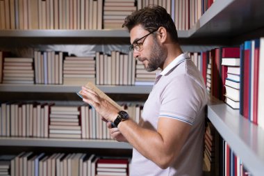 Orta yaşlı bir öğretmen ya da kütüphanede kitap okuyan bir profesör. Öğretmenler günü. Öğretmenim sınıfta. Yakışıklı öğretmenlerle bilgi ve eğitim. Sınıfta kitabı olan bir öğretmen. Öğretmen derste.