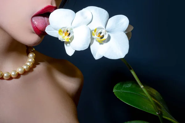 Sexy woman tongue lick flower. Orchid and woman lips. Orchid flower on sensual woman mouth
