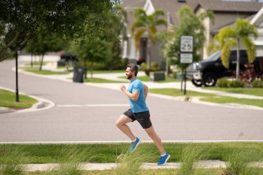 Spor habercisi. Adam kaçıyor. Açık havada koşan formda bir erkek spor modeli. Çekici bir adam hızlı koşuyor, dışarıda çalışıyor, Amerikan caddesinde koşuyor.
