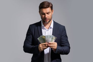 Üzerinde nakit para banknotları olan tişörtlü bir iş adamı sarı stüdyo geçmişinden izole edilmiş. 100 dolarlık banknot, finansal konsept.