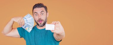 Bej renkli stüdyo pankartına para yatıran adam. Dolar banknotları olan takım elbiseli zengin bir adam. Dolar banknotlarıyla başarılı bir iş adamı