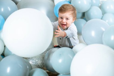 Bebek kucaklama balonları. Çocuk komik yüzlü hava balonları. Mavi balonlar, çocuklar için doğum günü süsü. Hayalci çocuk suratı. Hayalperest çocuk portresi yakın plan. Hayaller ve hayal gücü. Rüya gibi bebek yüzlü