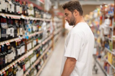 Şarap dükkanında içki şişelerini seçen bir adam. Marketteki ya da süpermarketteki adam.