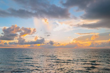 Deniz batımında bulutlu gökyüzü, okyanus sahilinde gün doğumu. Gün batımından sonra gökyüzünde gün batımı manzarası. Gökyüzüne ve denize karşı farklı renkte bulutlarla gün doğumu