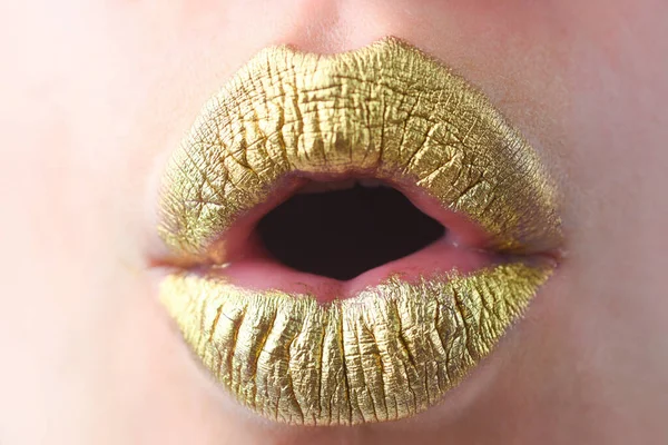 Surprised mouth. Close up woma face with gold lips. Gold paint on mouth. Golden lips. Luxury gold lips make-up. Golden lips with creative metallic lipstick. Gold metal lip. Sensual woman mouth